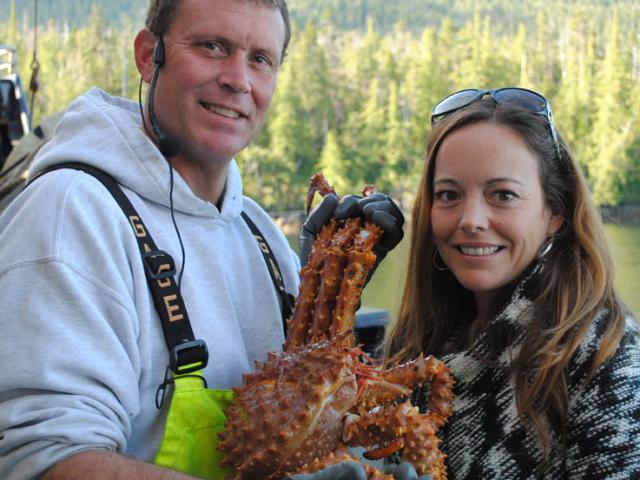 A woman holds a crab, with a little help, on the Deadliest Catch Crab Fisherman's Tour. Brave passengers on this favorite Alaskan Cruise excursion can take pictures with the daily catch.